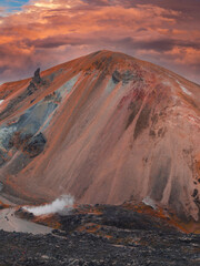 A vibrant mountain in Iceland's Landmannalaugar region with red, orange, and blue hues. Geothermal...