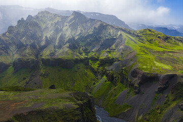 Aerial view of moss covered peaks and steep cliffs in Mulagljufur Canyon, Iceland. Light mist...