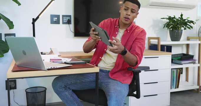 Noticing tablet errors, Diverse coworkers holding pages and typing notes on laptop in office lounge