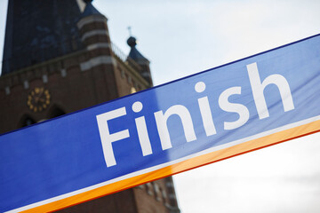 Sign marking the finish line at a running event in a historic town square during a sunny day