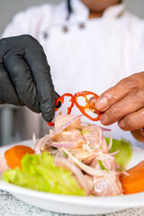 Chef garnishing traditional peruvian ceviche with red pepper
