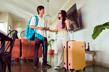Young latin american couple arriving at hotel lobby handing over passport and credit card to...