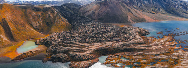 Aerial view of a volcanic terrain in Iceland with dark lava fields, turquoise and green lakes,...
