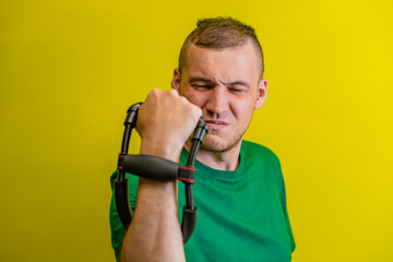 Determined Man Flexing Bicep With Hand Grip Exerciser Against Yellow Background