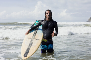 Latin surfer man rides the tropical waves in Mexico Latin America, hispanic people surfing in summer in sport activity concept 