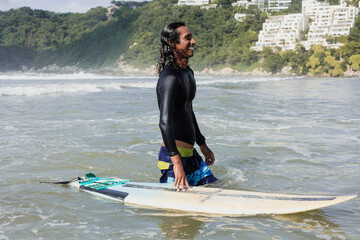 Latin surfer man rides the tropical waves in Mexico Latin America, hispanic people surfing in summer in sport activity concept 