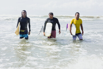 portrait of Latin surfers friends men with surfboard in the beach in Acapulco Mexico. Hispanic people surfing and having fun in summer sport activity in Latin America	