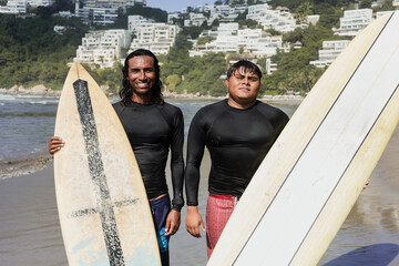 portrait of Latin surfers friends men with surfboard in the beach in Acapulco Mexico. Hispanic people surfing and having fun in summer sport activity in Latin America	