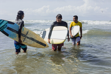 portrait of Latin surfers friends men with surfboard in the beach in Acapulco Mexico. Hispanic people surfing and having fun in summer sport activity in Latin America	