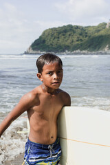portrait of latin child boy with surfboard on the beach in Mexico Latin America, hispanic kid surfing in summer sport activity