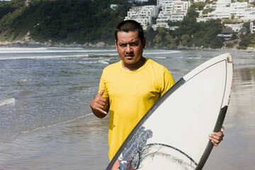 Latin surfer man rides the tropical waves in Mexico Latin America, hispanic people surfing in summer in sport activity concept 