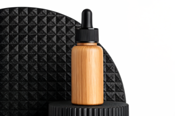 A cosmetic bamboo dropper bottle for serum or essential oil, presented on a black textured podium for product display.