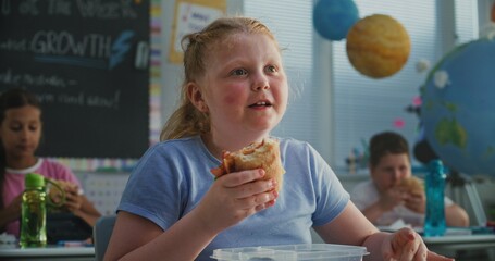 Young Girl Sitting at the Desk, Eating Yummy Homemade Sandwich from Lunch Box, Talking to Classmate...
