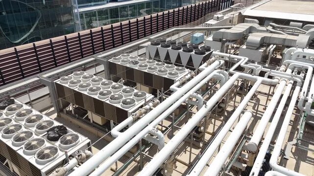 Aerial drone view of industrial HVAC systems, air conditioning units, ventilation fans, and piping on the rooftop 

