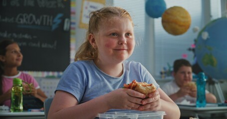 Young Girl Sitting at the Desk, Eating Yummy Homemade Sandwich from Lunch Box, Talking to Classmate...