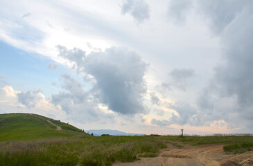 Serene mountain landscape featuring winding pathways amidst green hills with a backdrop of blue skies and clouds. Carpathian Mountains, Ukraine