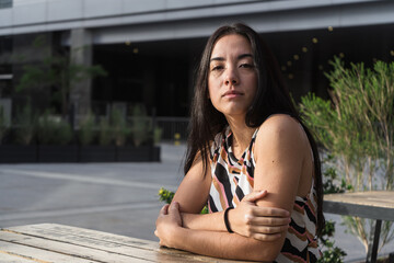 Young latin woman sitting at a table in an urban setting
