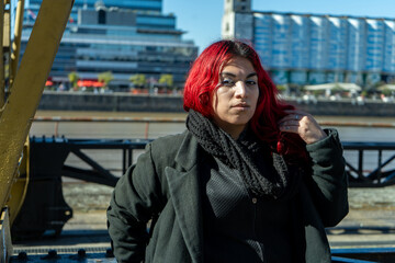 Stylish person with dyed red hair posing in puerto madero, buenos aires