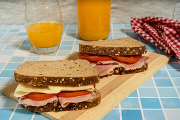 Healthy ham, cheese, and tomato sandwiches served on board with natural beverage