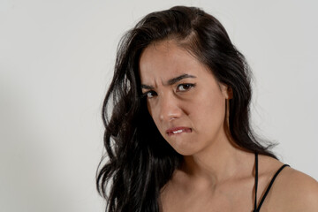 Young latin woman biting lip showing frustration and displeasure on white background