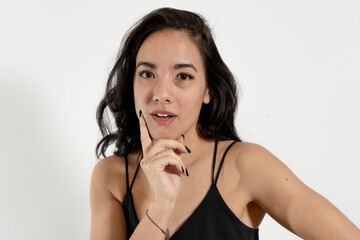 Pensive young woman touching chin in studio portrait