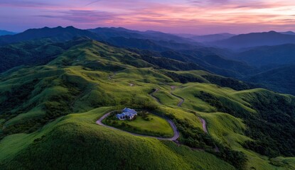 Obraz premium Mountaintop House Sunset Aerial View Winding road, green hills, purple sky, idyllic retreat