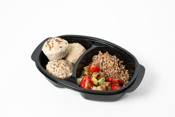 Top view of a healthy meal with steamed chicken meatballs, buckwheat, sautéed vegetables, and cherry tomatoes