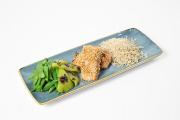 Grilled salmon in sesame crust with rice and green vegetables on a plate on a white background