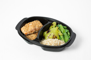 Grilled salmon in sesame crust with rice and green vegetables on a plate on a white background