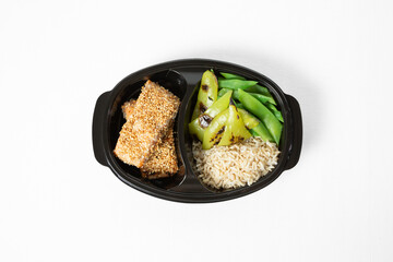 Grilled salmon in sesame crust with rice and green vegetables on a plate on a white background