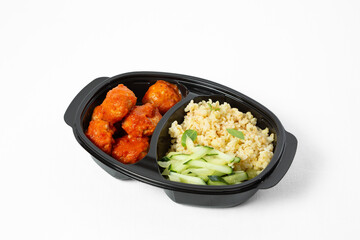 Bowl with bulgur, meatballs in tomato sauce, and fresh cucumber sticks on a white background. Top view