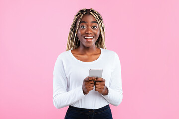 People And Technology Concept. Portrait of excited smiling young black woman using smartphone...