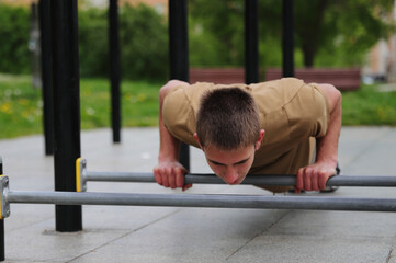 Young teenage male doing workout on sport bars, healthy lifestyle, outdoor fitness