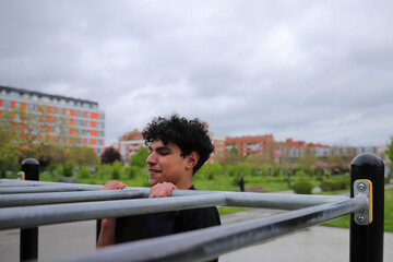 Young teenage male doing workout on sport bars, healthy lifestyle, outdoor fitness
