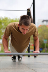 Young teenage male doing workout on sport bars, healthy lifestyle, outdoor fitness