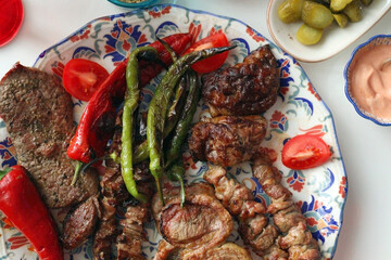 Turkish grilled meat platter with peppers and sauces