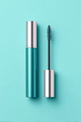 Stylish teal mascara tube with wand on a light blue background for beauty enthusiasts and makeup lovers