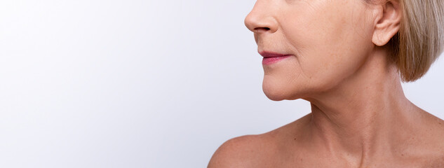 Mature skin rejuvenation concept. Cropped view of mature lady with naked shoulders on grey studio...
