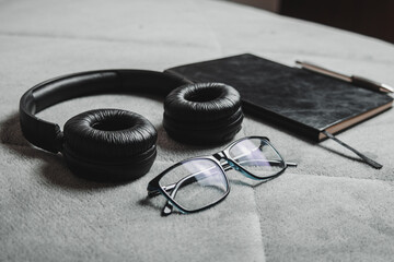 Notebook, pencil, headphones, glasses, camera, placed on a gray background.