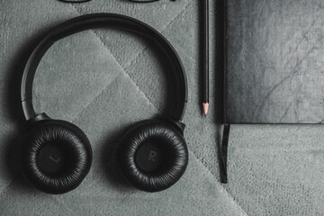 Notebook, pencil, headphones, glasses, camera, placed on a gray background.