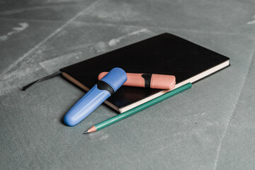 Notebook, pencil, headphones, glasses, camera, placed on a gray background.
