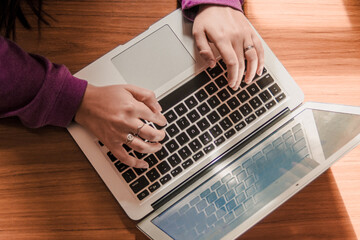 Young woman wearing a purple sweater using her computer for study at her desk. Remote work.