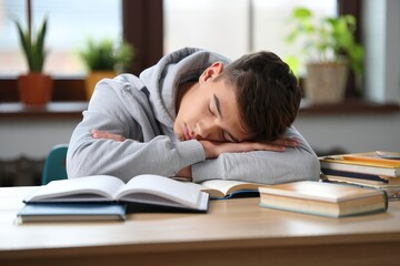 Exhausted student sleeping on desk after studying hard exam preparation concept