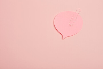 Pink paper speech bubble with a paperclip on monochrome pastel background