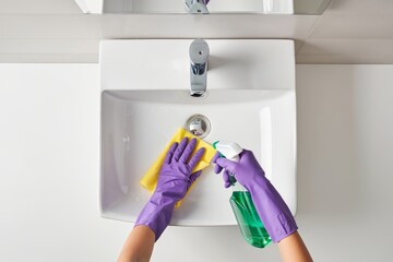 Cleaning bathroom sink with spray cleaner and cloth for hygiene and cleanliness