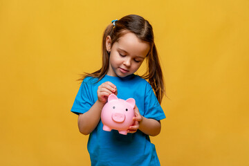 Banking, financial, investment and happy people concept - beautiful little girl puts coins into...