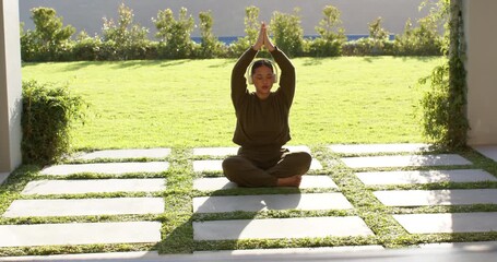 On start woman extending arms sideways, lifting into prayer position for meditation on grassy patio - Powered by Adobe