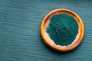 Organic spirulina powder in wooden bowl - Healthy food.