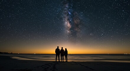 two people standing on a beach looking at the stars