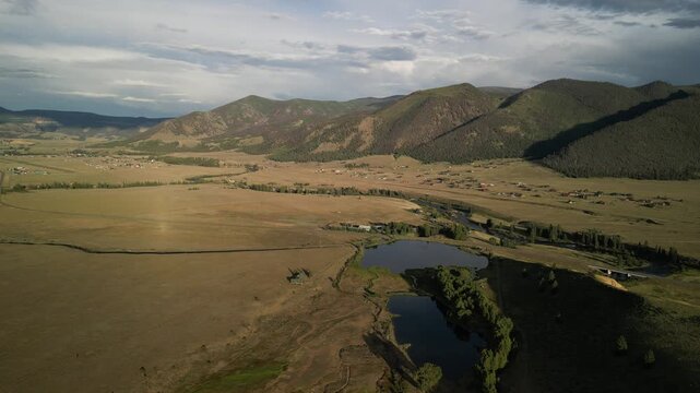 Aerial over rural properties and pond in Creede in San Juan Mountains at sunset